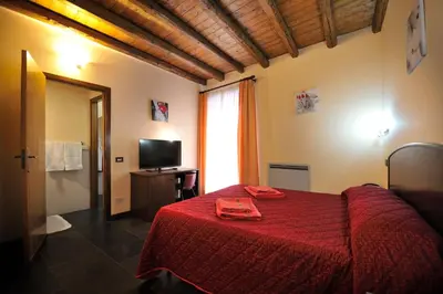 a bedroom with a red bed with a red blanket at Hotel Piccolo in Termini Imerese