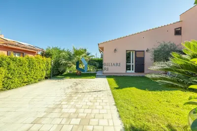 a house with a garden and a driveway at Villa Limuti con piscina condominiale in Campofelice di Roccella