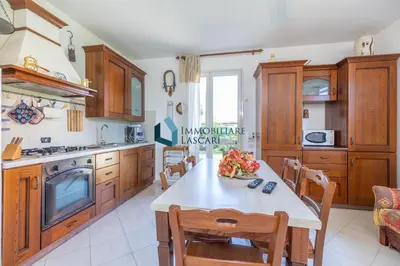 a kitchen with wooden cabinets and a table with chairs at Villa Limuti con piscina condominiale in Campofelice di Roccella