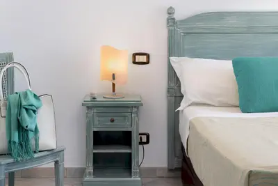 a bedroom with a bed with blue pillows on it at Hotel Riviera in San Vito lo Capo