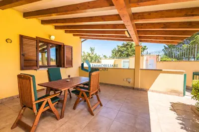 a wooden table and chairs on a patio at Villa Nettuno con piscina privata in Campofelice di Roccella