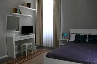 a bedroom with a bed and a desk with a television at Re Federico Apartment in Palermo