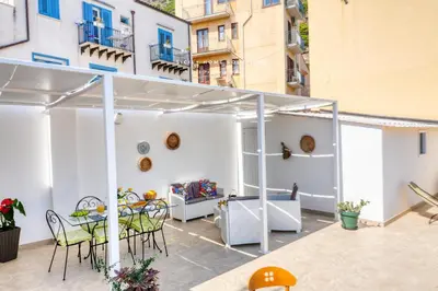 a patio with a table and chairs in a building at Casa dei Coralli Panoramic Sea View Centro Storico By Sicily Home Solutions in Castellammare del Golfo