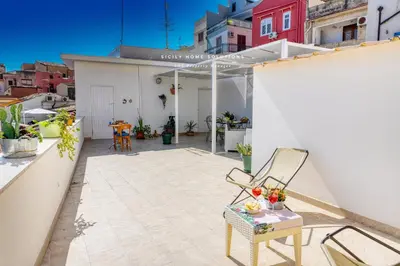 a balcony with a table and a chair on a roof at Casa dei Coralli Panoramic Sea View Centro Storico By Sicily Home Solutions in Castellammare del Golfo