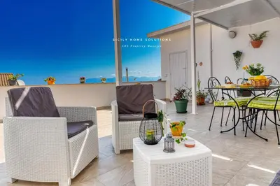 a patio with a table and chairs and an umbrella at Casa dei Coralli Panoramic Sea View Centro Storico By Sicily Home Solutions in Castellammare del Golfo