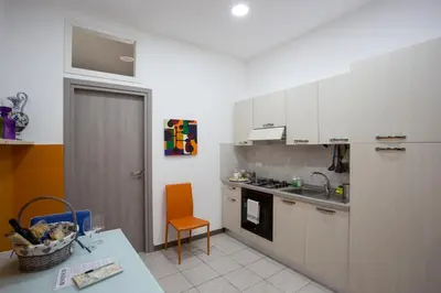 a kitchen with white cabinets and an orange chair at Casa Florio Appartamenti in Palermo