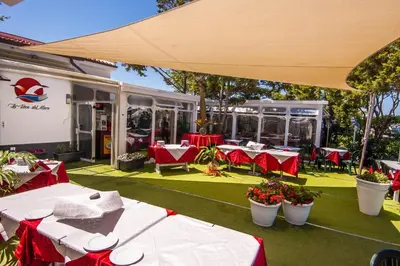 an outdoor patio with tables and chairs and a building at Villa Barbara...a 100 passi dal mare!!!! in Lascari