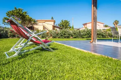a red chair sitting on the grass next to a pool at Villa Pasquale...immersa nella tranquillita' in Lascari