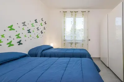 two beds in a bedroom with blue sheets and butterflies on the wall at Villa Francesco...graziosa, moderna, confortevole! in Lascari
