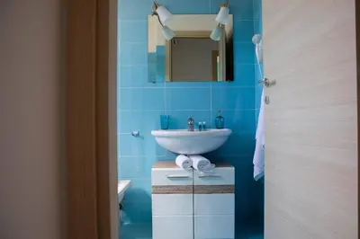 a blue bathroom with a sink and a mirror at Riva Sea Apartments in Castellammare del Golfo