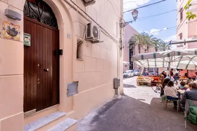 an alley in a city with people sitting at tables at Arianna's House Historical Market in Palermo