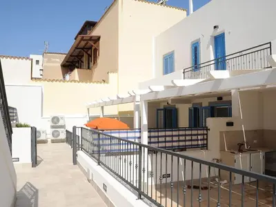 a balcony of a white building with an orange umbrella at Appartamento Irma Dario in San Vito lo Capo