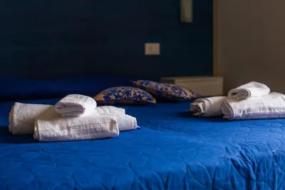 three towels are sitting on a blue bed at Elisir Suite Rooms by Marino Tourist in San Vito lo Capo