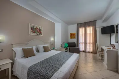 a hotel room with a large bed and a desk at Helios Hotel in San Vito lo Capo