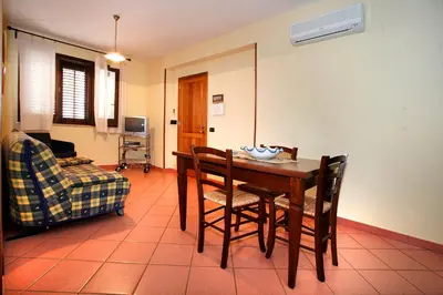 a dining room with a table and chairs and a couch at La Chiusa Case Vacanze in Castellammare del Golfo