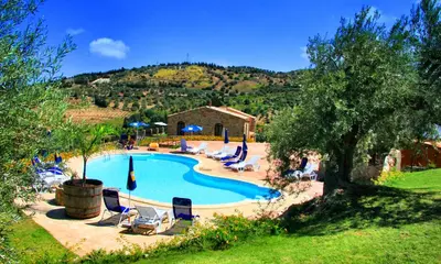 a large swimming pool with chairs and a house at Poggio Pozzetti in Lascari