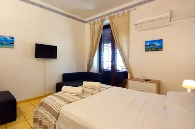 a bedroom with a white bed and a television at Porta Carini Residence in Palermo