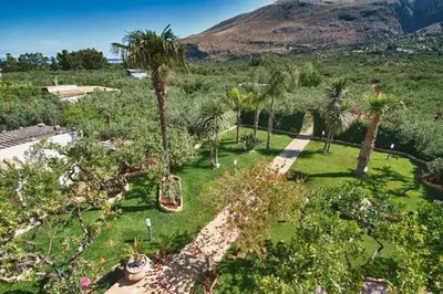 an aerial view of a park with palm trees and a mountain at ilgiardinodellanonna in Castelluzzo
