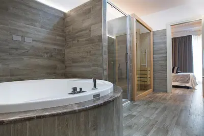 a bathroom with a bath tub and a bedroom at Palazzo Ducale Suites in Monreale