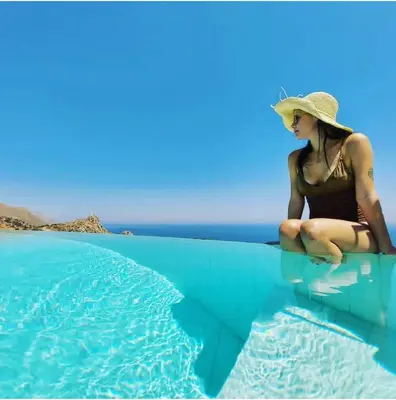 a woman in a hat sitting on the water at Hotel Antica Cascina Del Golfo in Scopello