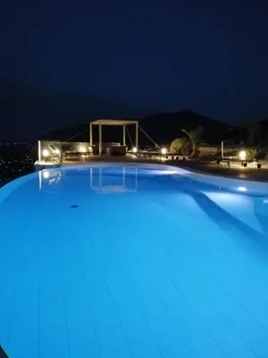 a large blue swimming pool at night at Hotel Antica Cascina Del Golfo in Scopello