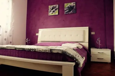 a bedroom with a white bed with purple walls at Villa Aga in Campofelice di Roccella