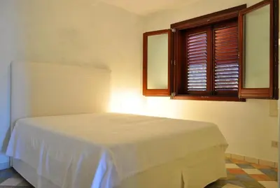 a bedroom with a white bed in a room with a window at Villa Le Meraviglie in San Vito lo Capo