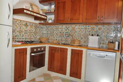 a kitchen with wooden cabinets and a white dishwasher at Villa Le Meraviglie in San Vito lo Capo