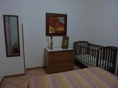 a bedroom with a crib and a dresser with a mirror at Appartamento Marconi 15 in San Vito lo Capo
