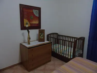 a bedroom with a crib and a dresser next to a crib at Appartamento Marconi 15 in San Vito lo Capo