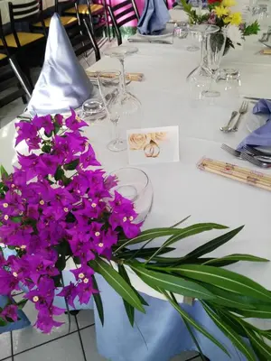a table with purple flowers on a white table cloth at Camping Village La Pineta in San Vito lo Capo