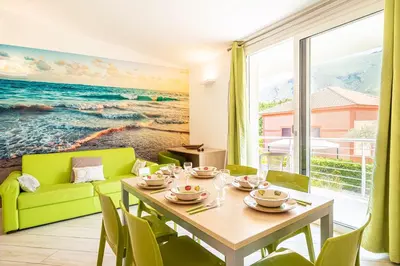 a dining room with a table and a green couch at Borgo Aranci - Villetta a schiera Lavanda - A8 in Castellammare del Golfo