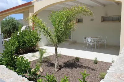 a patio with a palm tree and a table at Borgo Aranci - Villetta Peonia B3 - Castellammare del Golfo in Castellammare del Golfo