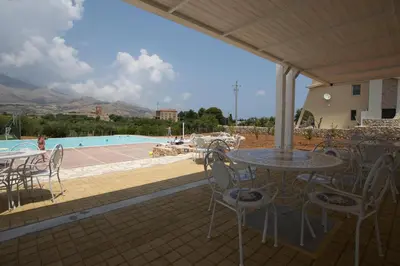 a patio with a table and chairs and a pool at Borgo Aranci - Villetta Peonia B3 - Castellammare del Golfo in Castellammare del Golfo