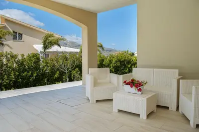 a patio with white chairs and a table with flowers at Borgo Aranci - Villa Tulipano in Castellammare del Golfo