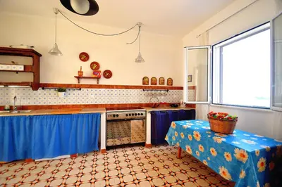 a kitchen with blue drapes and a table in it at Villa Calamazzo in Scopello