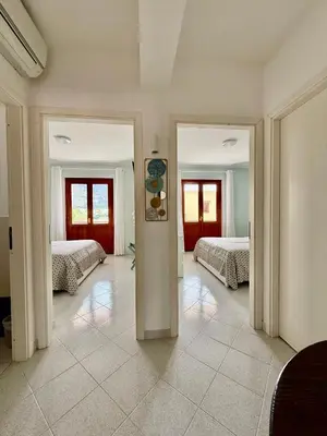 a room with two beds and a hallway with two mirrors at Yucca Apartment in San Vito lo Capo