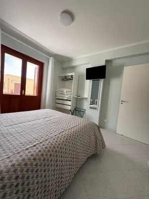 a bedroom with a bed and a window and a door at Yucca Apartment in San Vito lo Capo