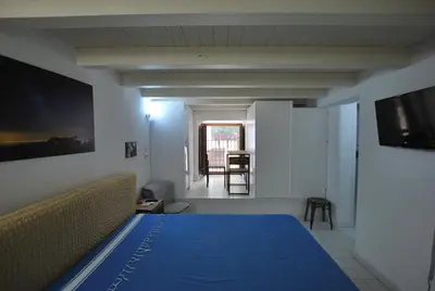 a bedroom with a blue bed and a living room at Discesa Delle Capre Studio Confort in Palermo