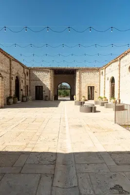 an empty courtyard with an arch in a brick building at Tenute Baglio Passofondo in Alcamo