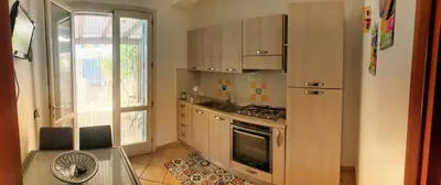 a kitchen with wooden cabinets and a sink and a window at appartamento residence via giardini Acquamarina in San Vito lo Capo
