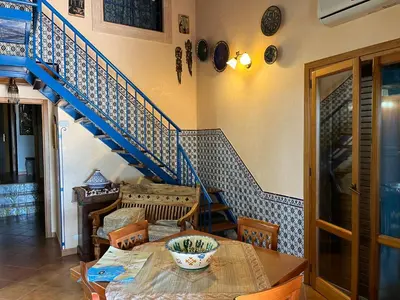 a dining room with a table and a blue staircase at Villa vista MARE a MÀKARI in San Vito lo Capo