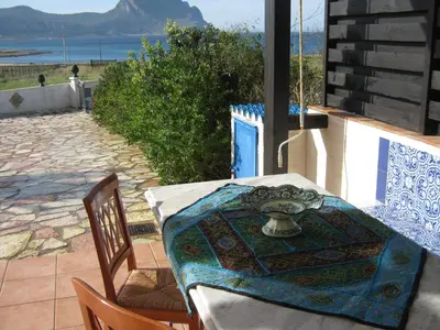 a table and chairs on a patio with a view of the ocean at Villa vista MARE a MÀKARI in San Vito lo Capo