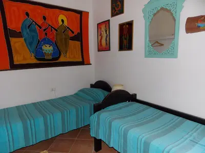 a bedroom with two beds and a painting on the wall at Villa vista MARE a MÀKARI in San Vito lo Capo
