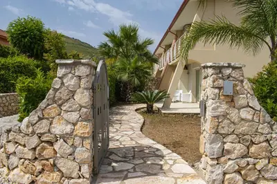 a stone wall with a gate in front of a house at Borgo Aranci - Villetta a Schiera A1 in Castellammare del Golfo