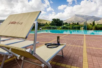 a bench with a laptop sitting on it next to a pool at Borgo Aranci - Villetta a Schiera A1 in Castellammare del Golfo