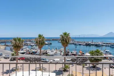 a marina with palm trees and boats in the water at Stenopus Greco Casa per AFFITTI TURISTICI in Santa Flavia