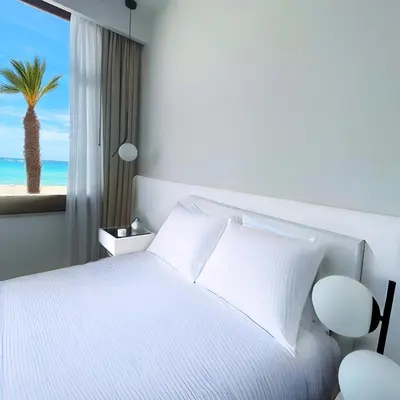 a bedroom with a white bed and a palm tree at Hotel Egitarso Sul Mare in San Vito lo Capo