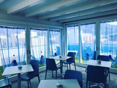 a restaurant with tables and chairs and windows at B&B Acqua Azzurra in San Vito lo Capo