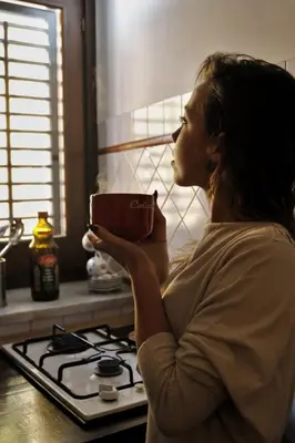 a woman holding a coffee cup in a kitchen at Casa Palazzo Reale in Palermo